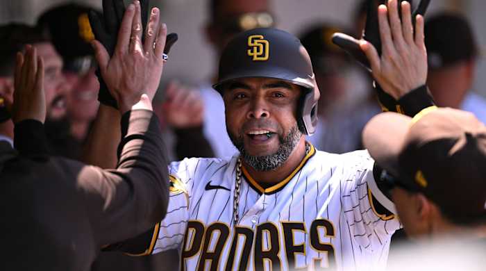 Padres designated hitter Nelson Cruz high fives his teammates in a dugout during a game.